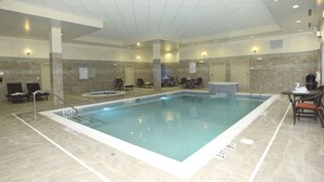 Una piscina interior con sillones de descanso y una mesa cerca de la piscina.