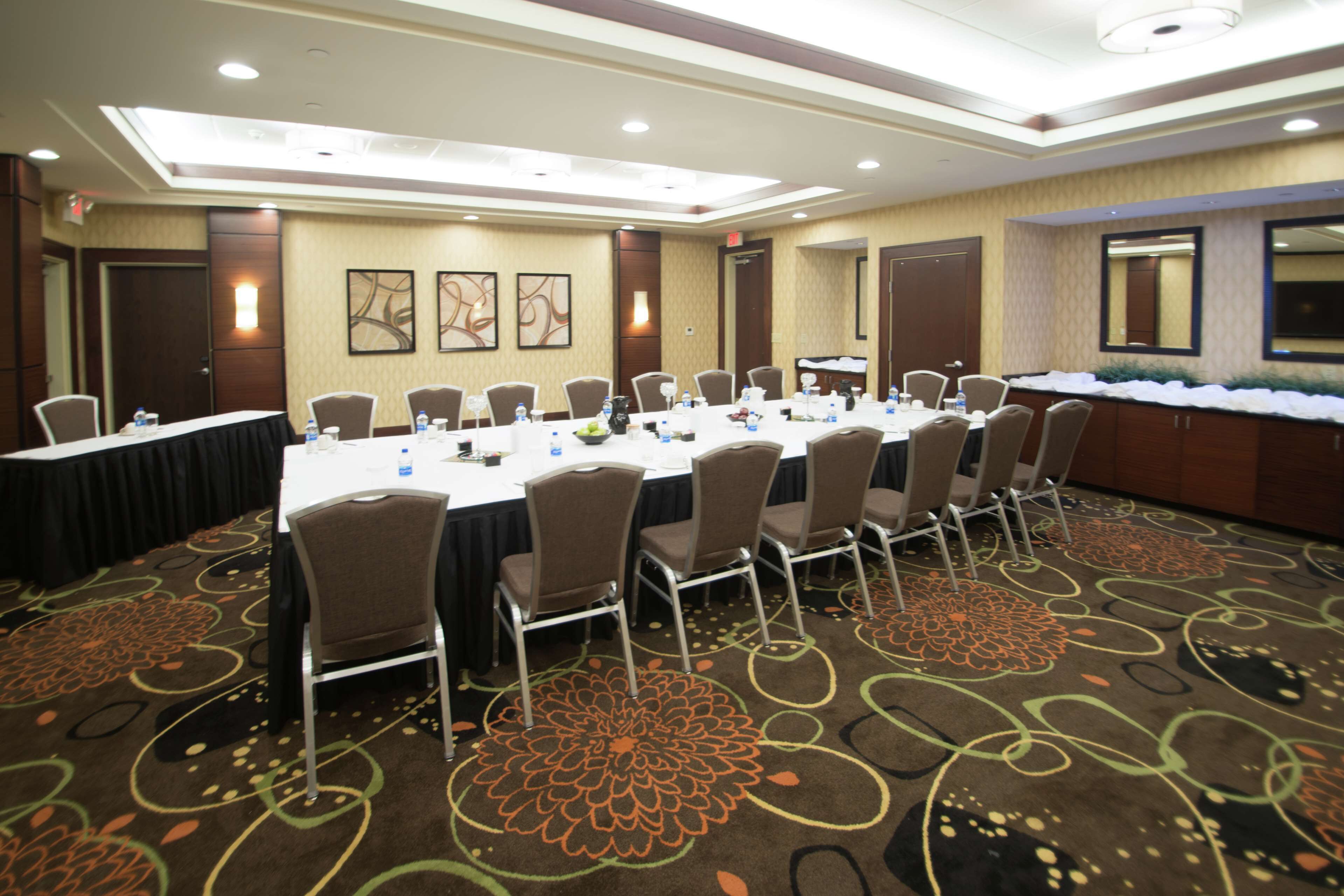 A conference room with a long table, chairs, and a carpeted floor.