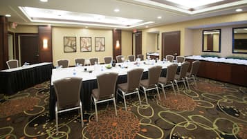 A conference room with a long table, chairs, and a carpeted floor.