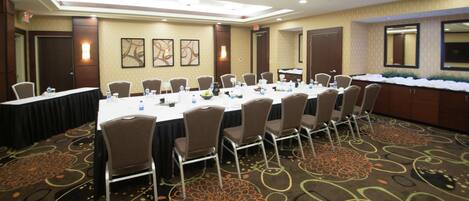 A conference room with a long table, chairs, and a carpeted floor.