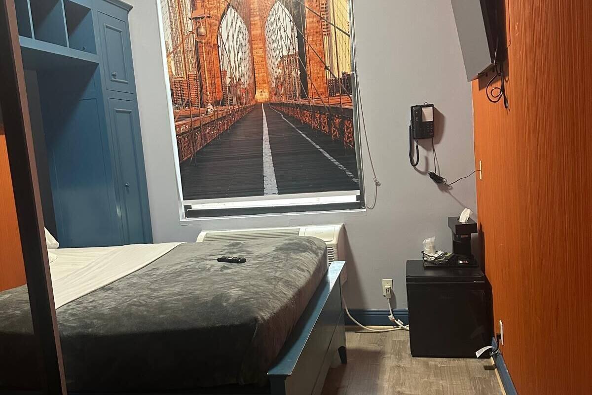 Une chambre à coucher comprenant un lit, un bureau, une chaise, un téléviseur et une fenêtre donnant sur un pont.