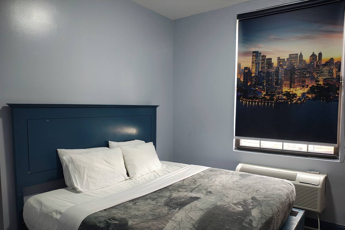 Une chambre à coucher avec un lit, une vue sur la ville et une fenêtre avec des stores.