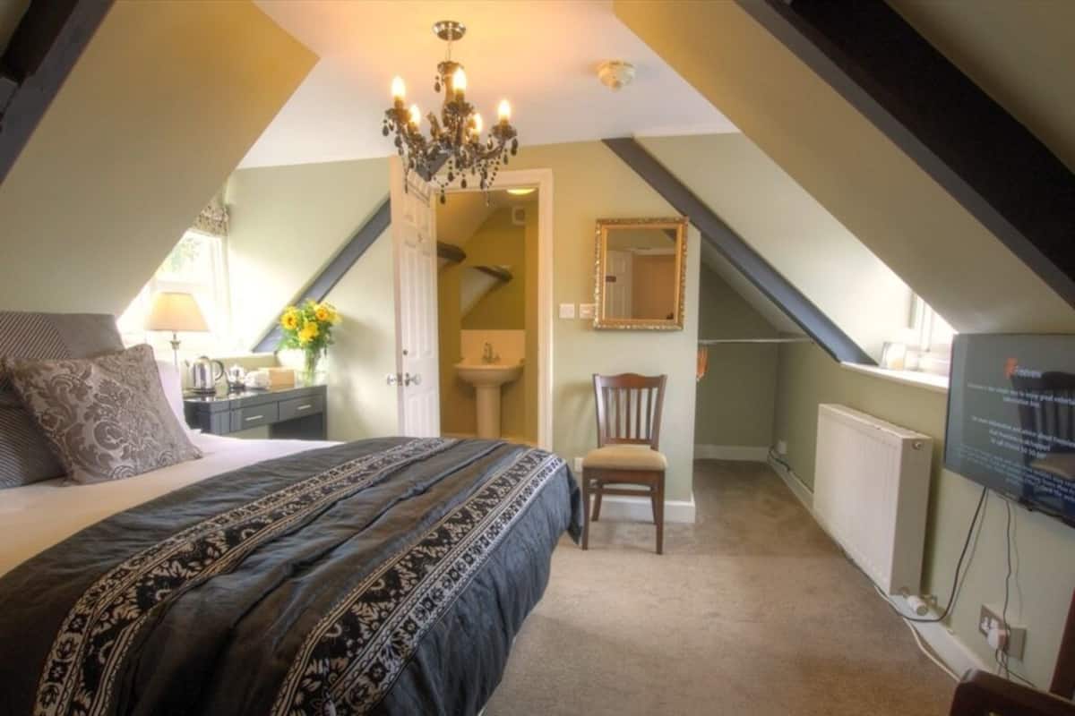 A bedroom with a large bed, a chair, a dresser, a mirror, and a radiator.