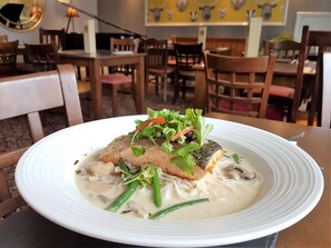 A white plate with a fish dish, green beans, and mushrooms. - Dunster Castle Hotel (Minehead)