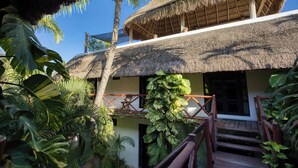 A thatched-roof building with a wooden staircase and lush tropical vegetation. - Kin Ha Tulum Hotel (Tulum)