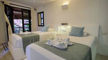A hotel room with two beds, a window with curtains, a bedside table with a lamp, and a view of the outside.