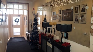 A hallway with a Christmas tree, framed pictures on the wall, and a door with a wreath. - The Fame (Blackpool)