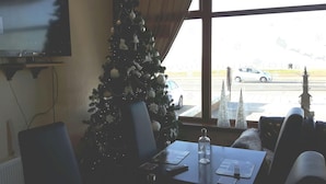 A room with a Christmas tree, a TV on the wall, a table with a laptop, a bottle, and a glass. - The Fame (Blackpool)