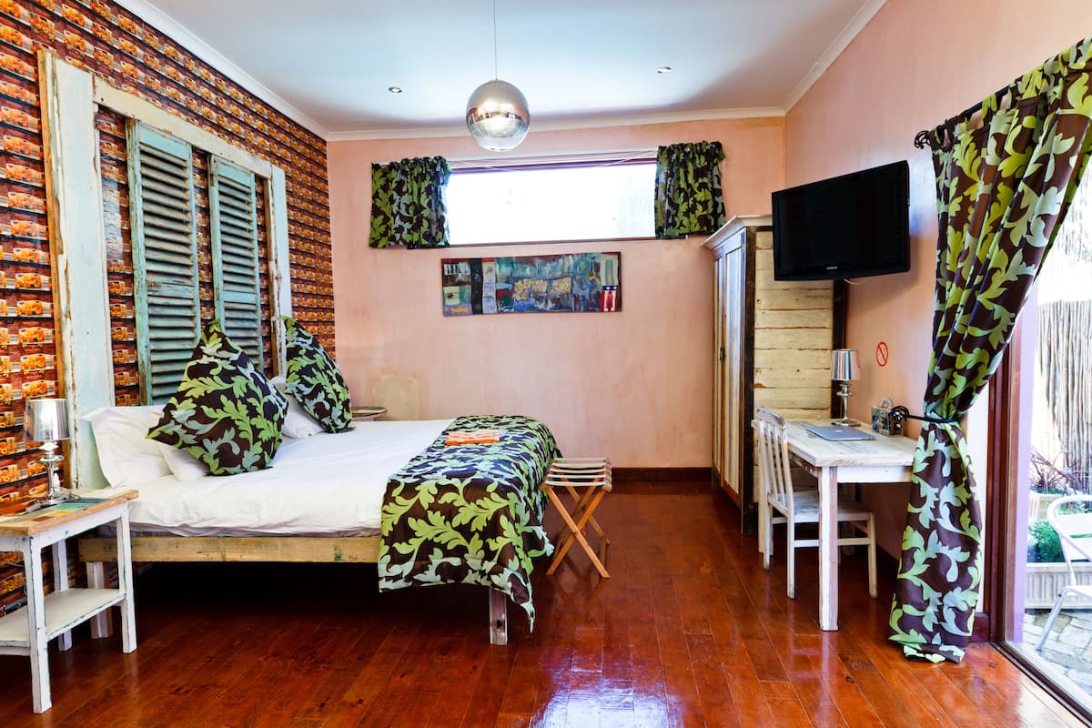 Un dormitorio con cama, escritorio, televisor y ventana con cortinas.