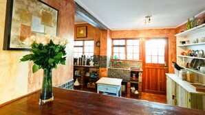 A rustic kitchen with wooden cabinets, a vase of flowers, and a window with a view. - Sweet Olive Guesthouse (Cape Town)