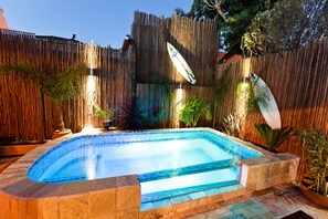 A rectangular swimming pool with a tiled edge, surrounded by a wooden fence and potted plants. - Sweet Olive Guesthouse (Cape Town)