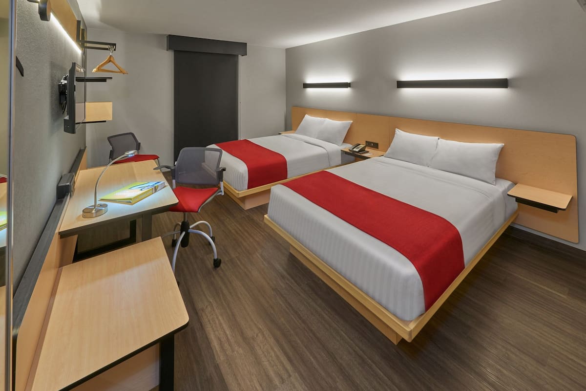 Une chambre d’hôtel avec deux lits, un bureau, une chaise, une armoire et une table de chevet.