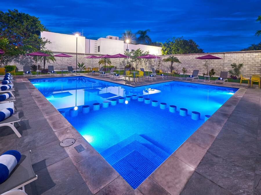 Una piscina al aire libre, sombrillas, sillones reclinables de piscina