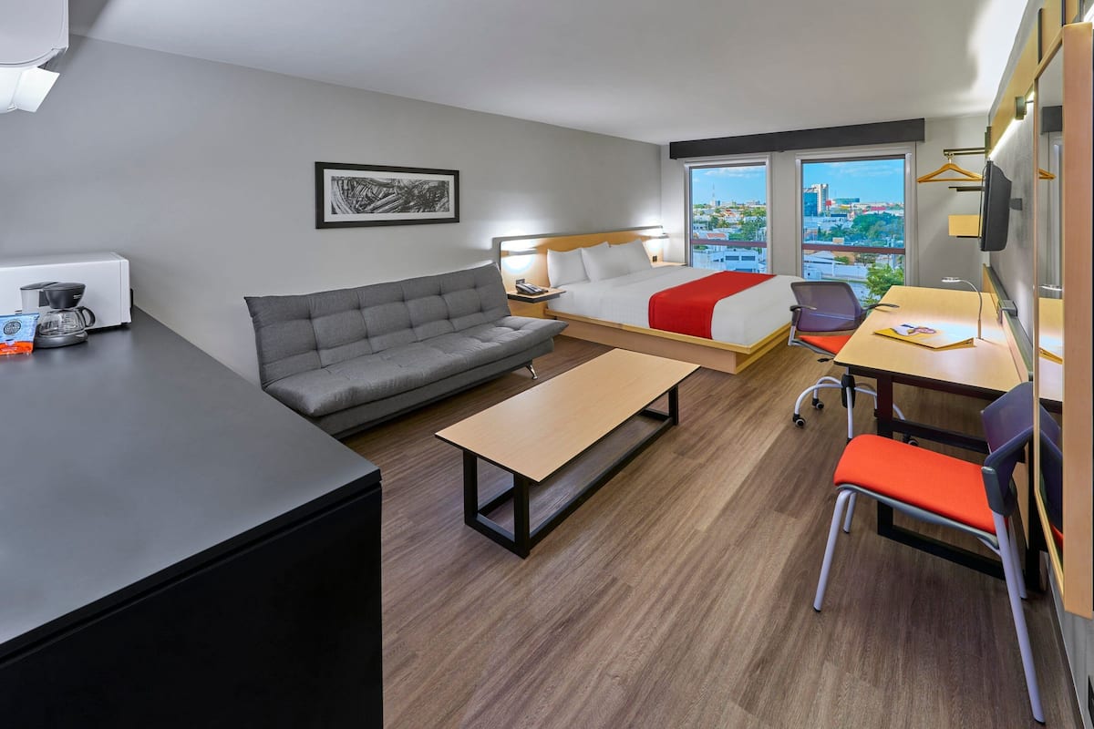 Une chambre d’hôtel moderne équipée d’un canapé, d’un lit, d’une table à manger et offrant une vue sur la ville.