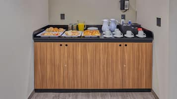 A breakfast buffet with pastries, juice, and coffee.