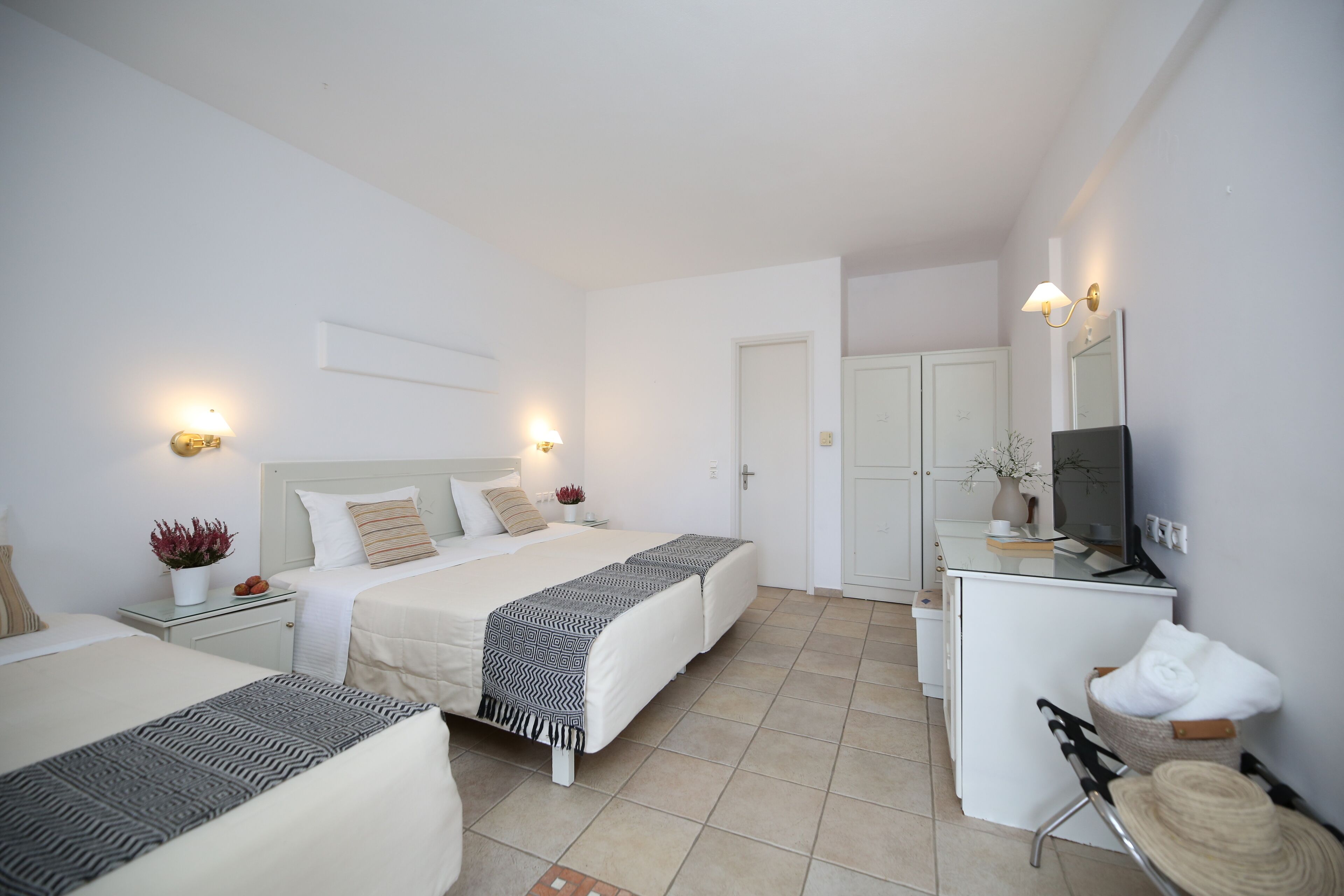 Habitación de hotel con dos camas, un escritorio, una silla, un televisor y la puerta del baño.