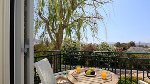 A balcony with a table set for two, featuring a plate of fruit and two glasses of orange juice. - Astir of Naxos (Naxos)