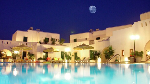 A nighttime view of a resort with a swimming pool, sun loungers, and umbrellas. - Astir of Naxos (Naxos)