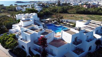 A white building with a rooftop pool and outdoor seating.