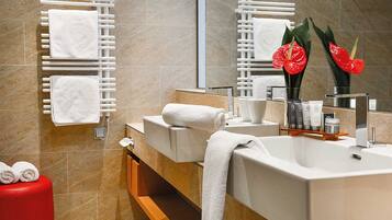 Une salle de bain moderne avec deux lavabos, des serviettes blanches, un tabouret rouge et un miroir décoré de fleurs rouges.