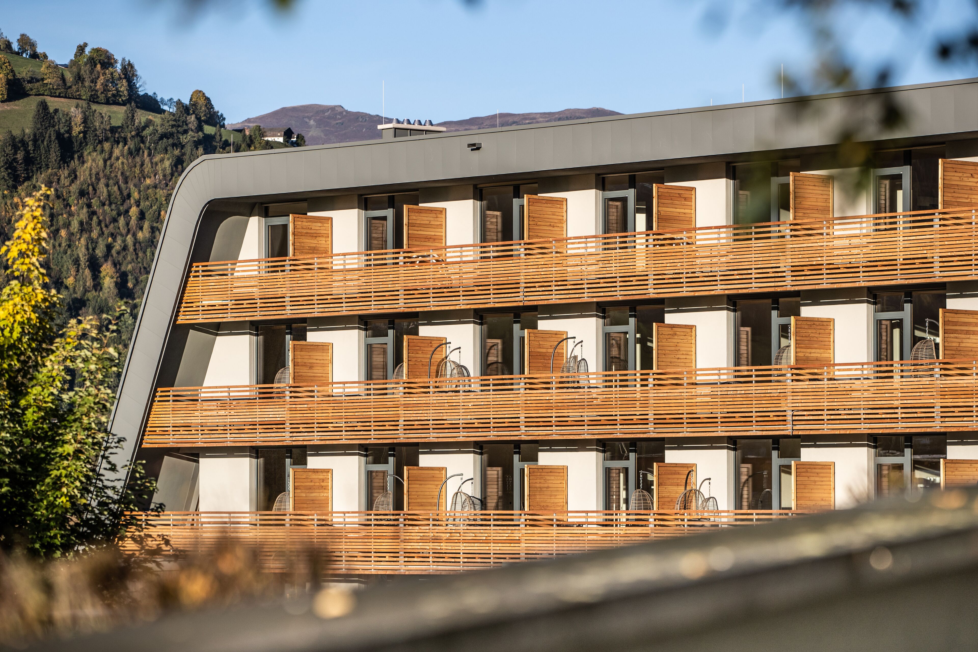 Un bâtiment moderne doté de nombreux balcons, de grandes fenêtres et offrant une vue sur un paysage vallonné.
