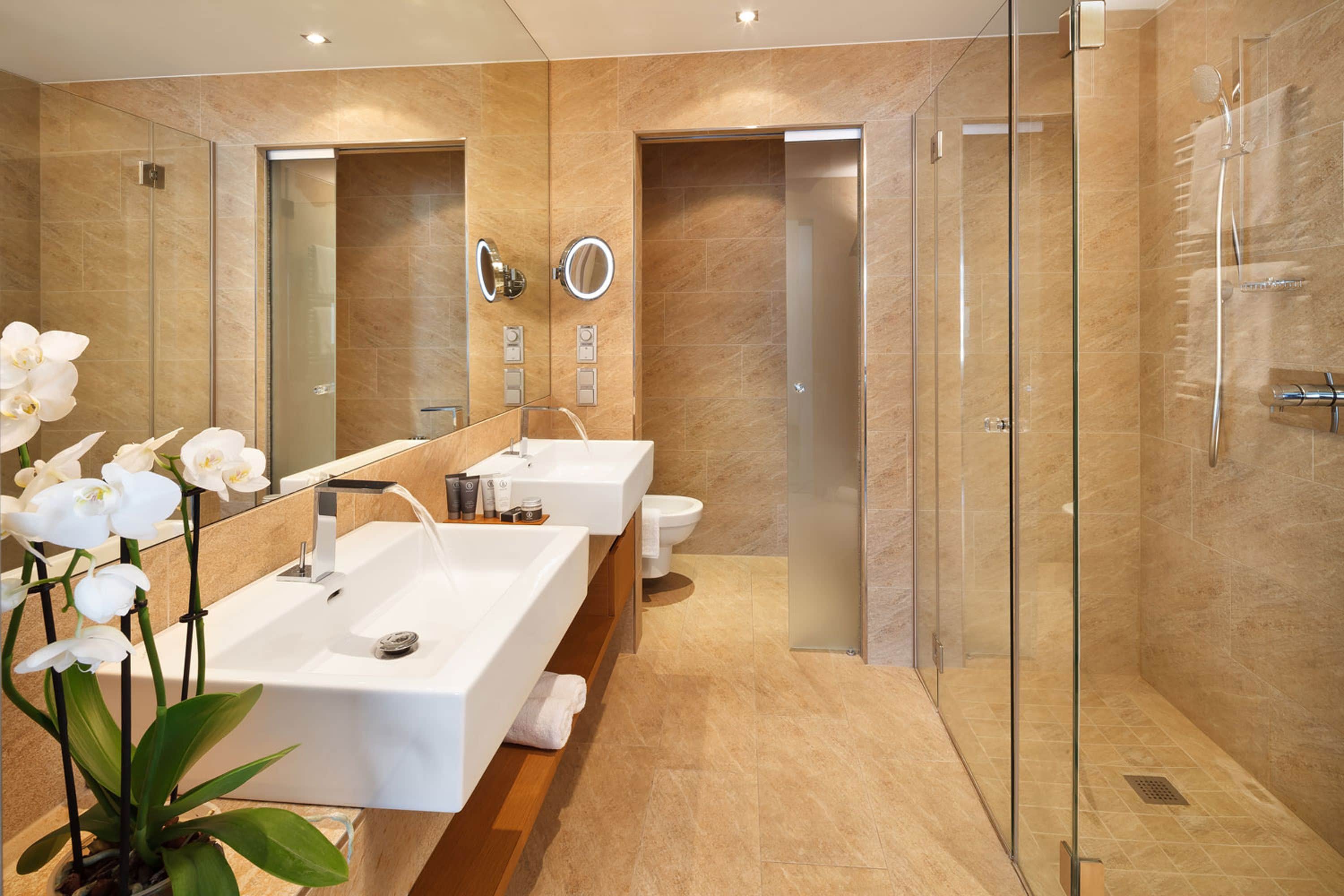 A modern bathroom with two sinks, a glass shower enclosure, and a large mirror.