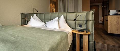 Une chambre d’hôtel avec un grand lit, deux tables de chevet, un bureau en bois et un rideau.