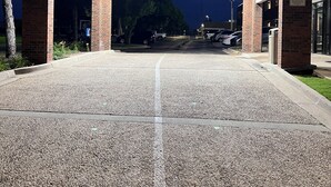 A building entrance with a gravel driveway, brick pillars, and overhead lighting. - Motel 6 Oklahoma City, OK - Fairgrounds West (Oklahoma City)