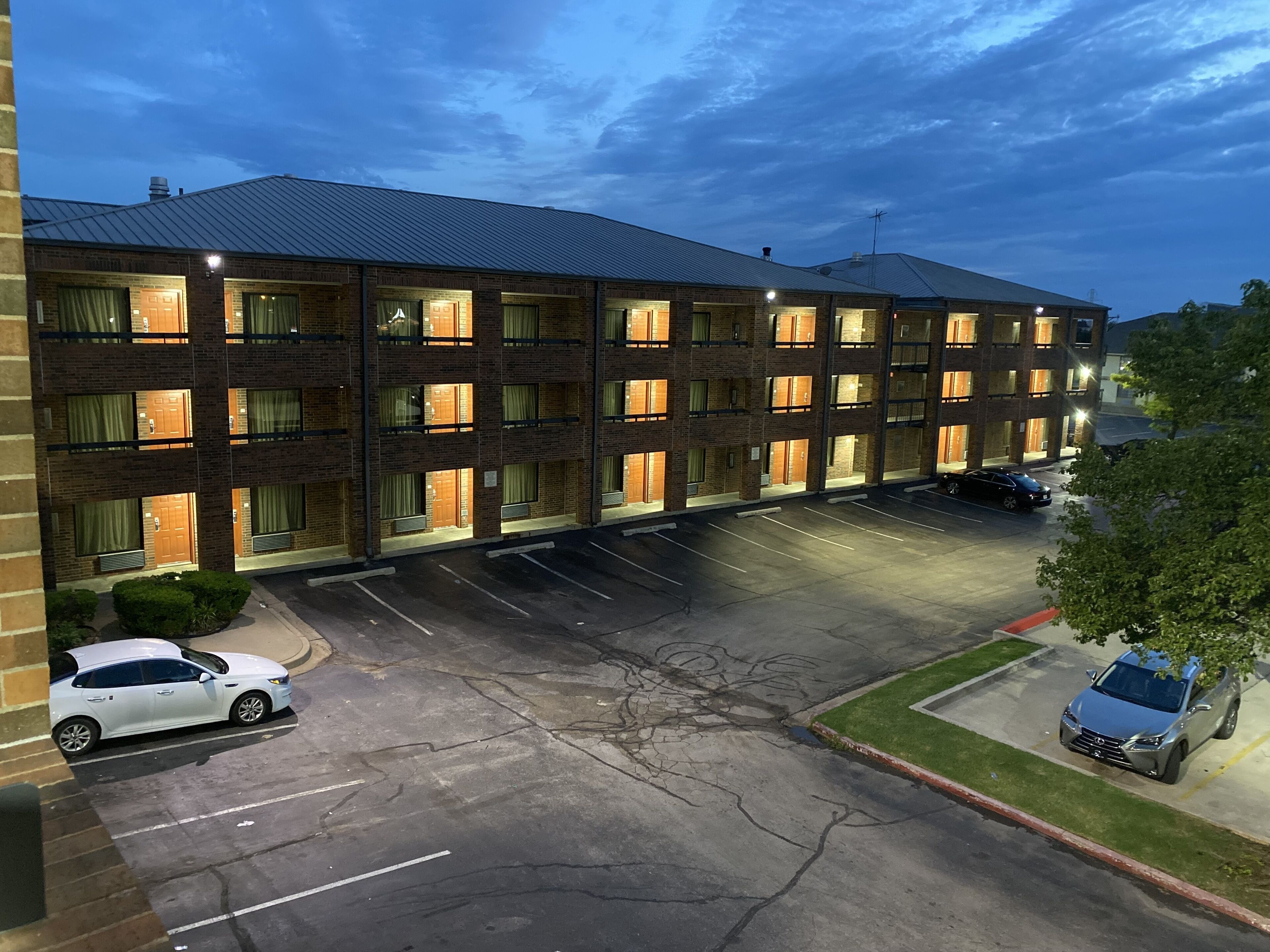 A multi-story hotel with a parking lot and a few cars parked.