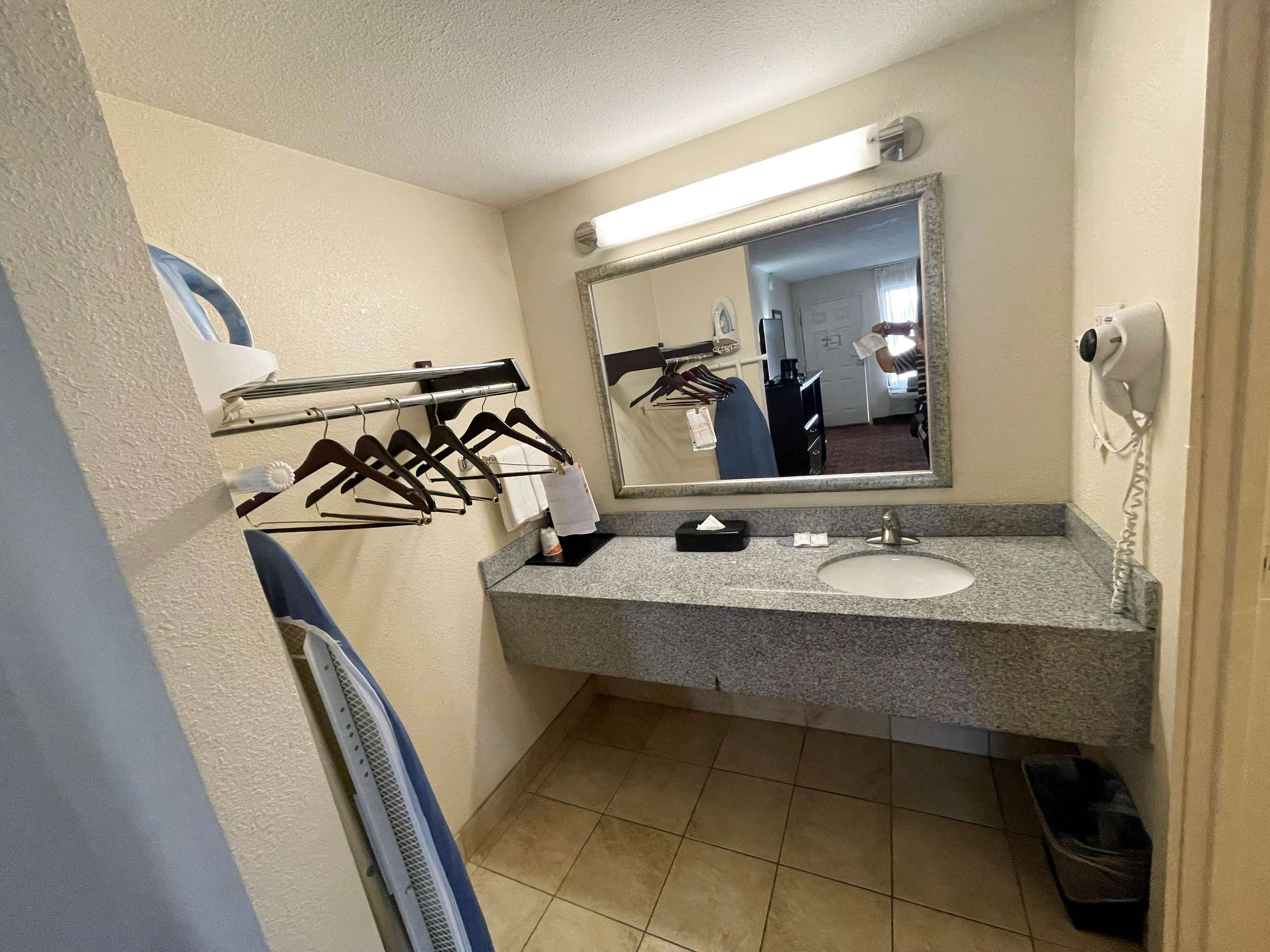 Een badkamer met een wastafel, spiegel, handdoekhouder en een haardroger.