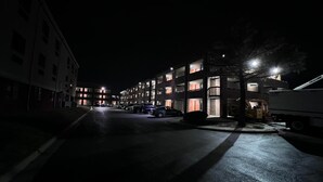 A nighttime view of a multi-story parking garage with illuminated windows and a few parked cars. - Motel 6 Oklahoma City, OK - Fairgrounds West (Oklahoma City)