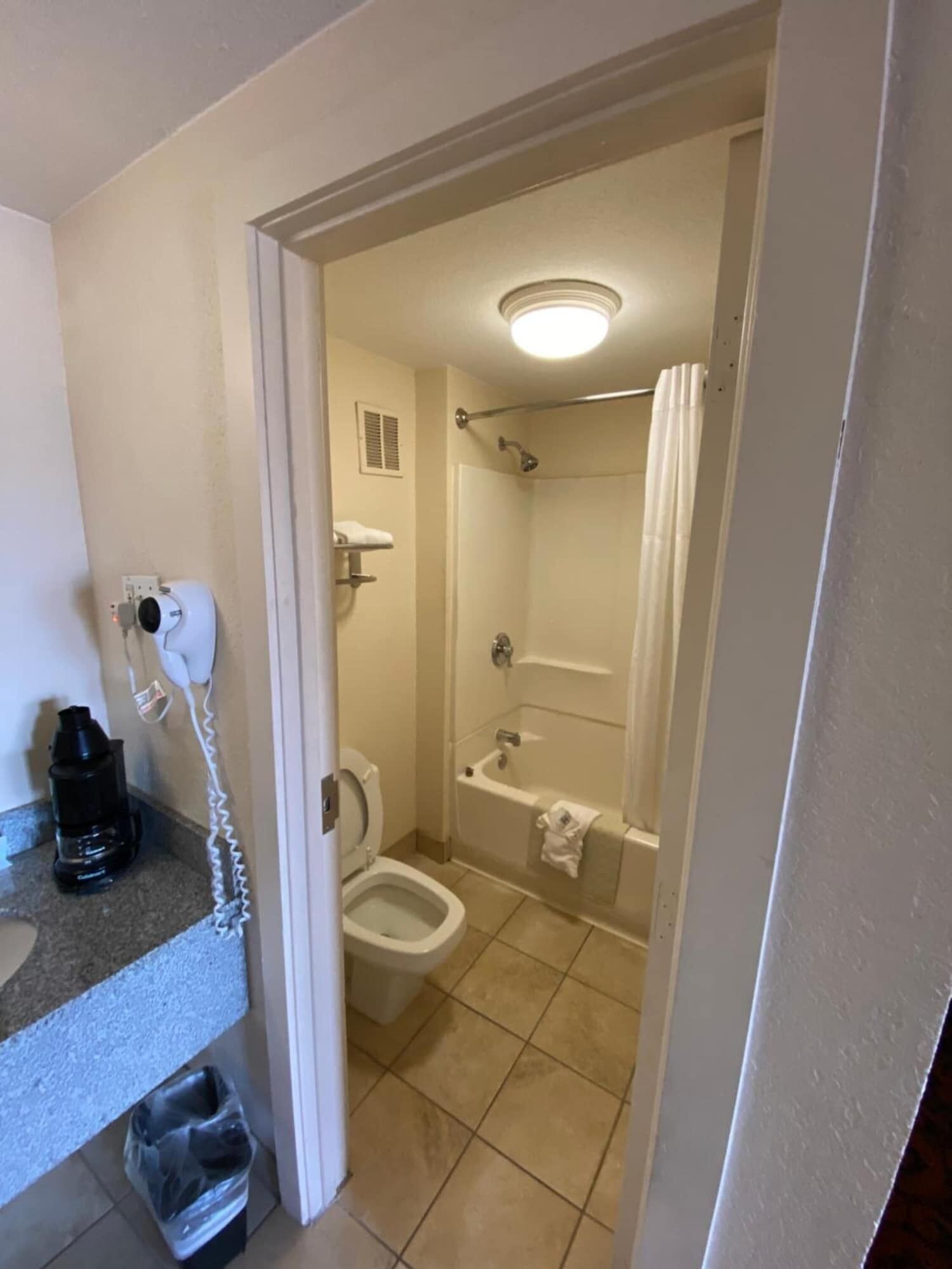 Ein Badezimmer mit Toilette, Waschbecken, Dusche und Mülleimer.