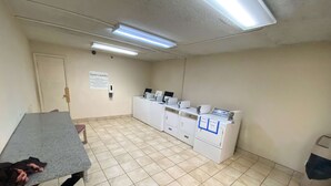 A laundry room with a table, a sign for guest laundry, and multiple washing machines. - Motel 6 Oklahoma City, OK - Fairgrounds West (Oklahoma City)