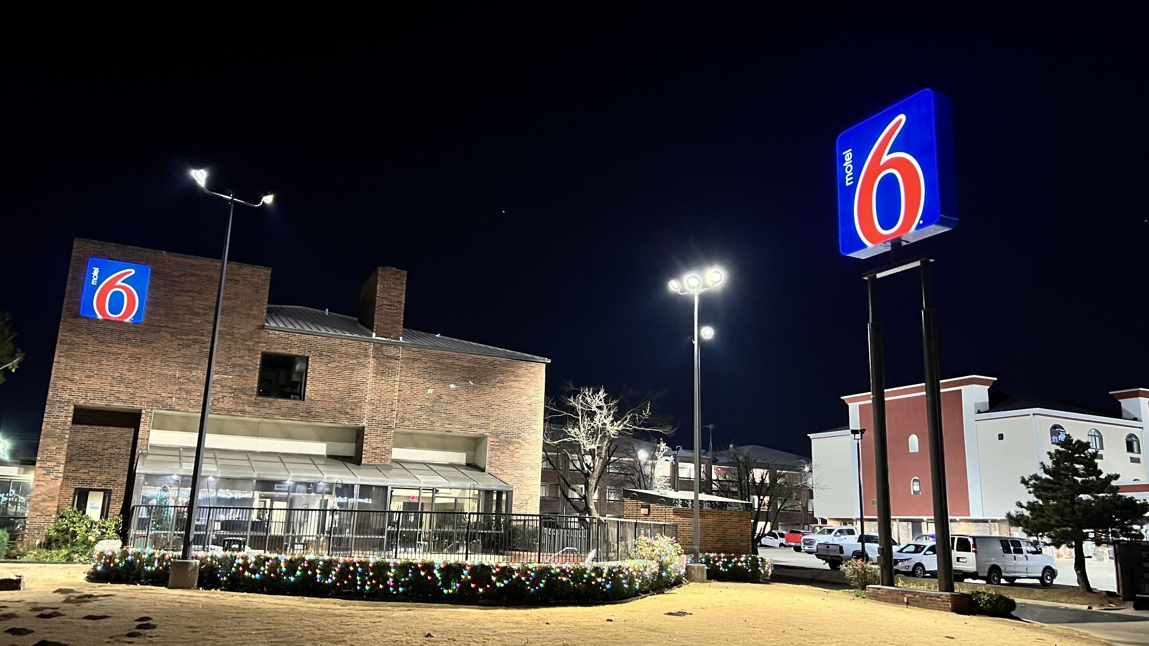 A motel with a prominent '6' sign, a brick building, and a parking lot.