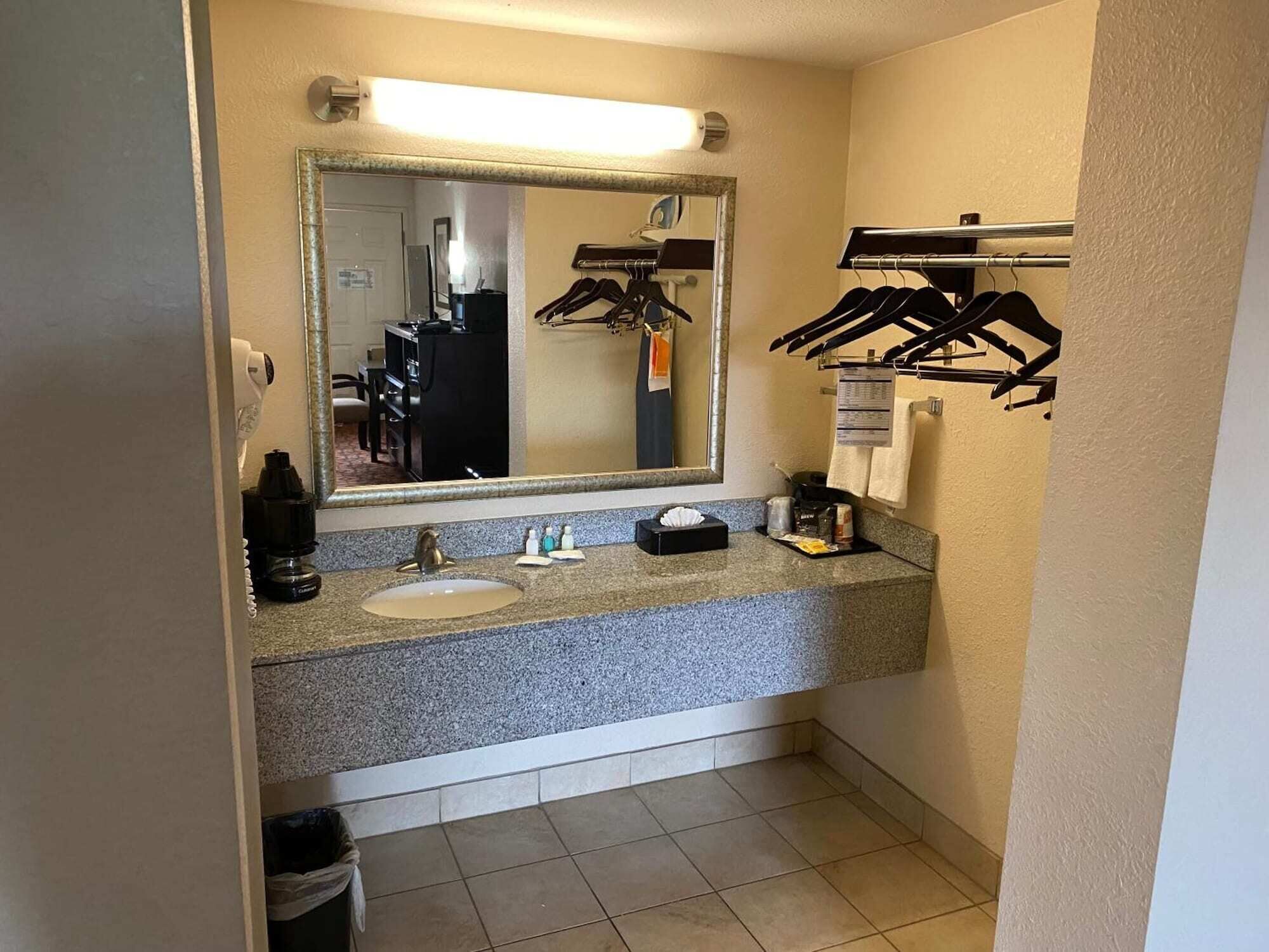 A bathroom with a granite countertop, a sink, a mirror, and a towel rack.
