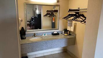 A bathroom with a granite countertop, a sink, a mirror, and a towel rack.