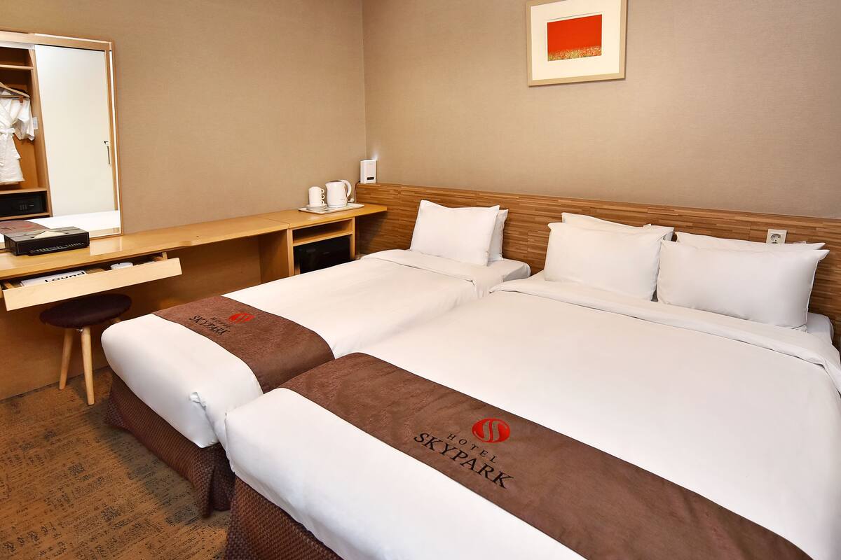A hotel room with a large bed, a wooden desk, a mirror, and a framed picture on the wall.