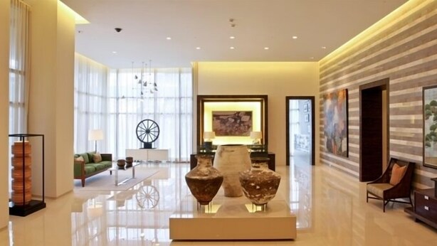 A spacious lobby with a modern design, featuring a large chandelier, a green sofa, and a display of decorative vases. - Joya Lofts and Towers (Makati)