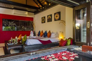 Quarto de hotel com cama, almofadas, mesa de cabeceira, janela e decoração na parede.