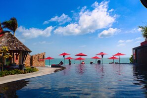 A poolside area with a clear view of the sea, red umbrellas, and a thatched-roof structure. - Kirikayan Boutique Resort (Koh Samui)