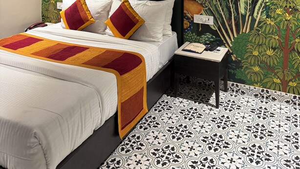 A bedroom with a bed, a nightstand, a telephone, and a ceiling fan. - Hotel Raghuraj Palace (Jaipur)