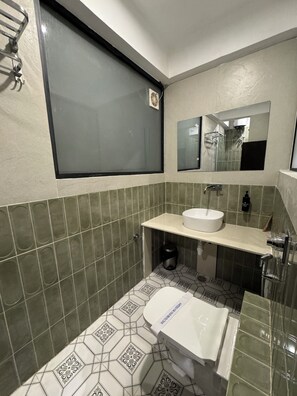 A bathroom with a toilet, sink, and a window. - Hotel Raghuraj Palace (Jaipur)