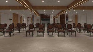 A spacious hall with rows of wooden chairs, a polished floor, and modern lighting fixtures. - Hotel Raghuraj Palace (Jaipur)