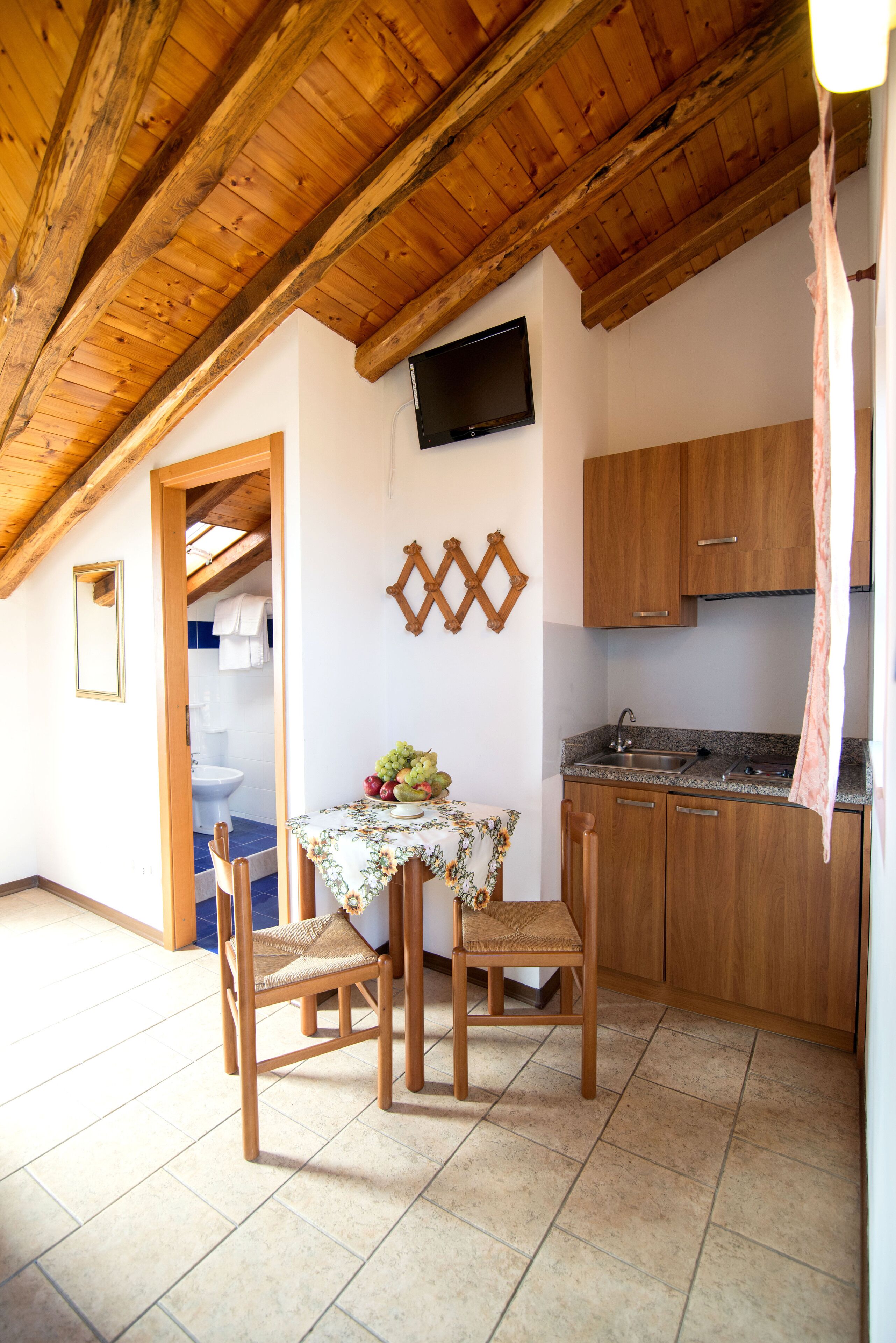 Une petite cuisine avec des meubles en bois, un évier et une table avec des chaises.