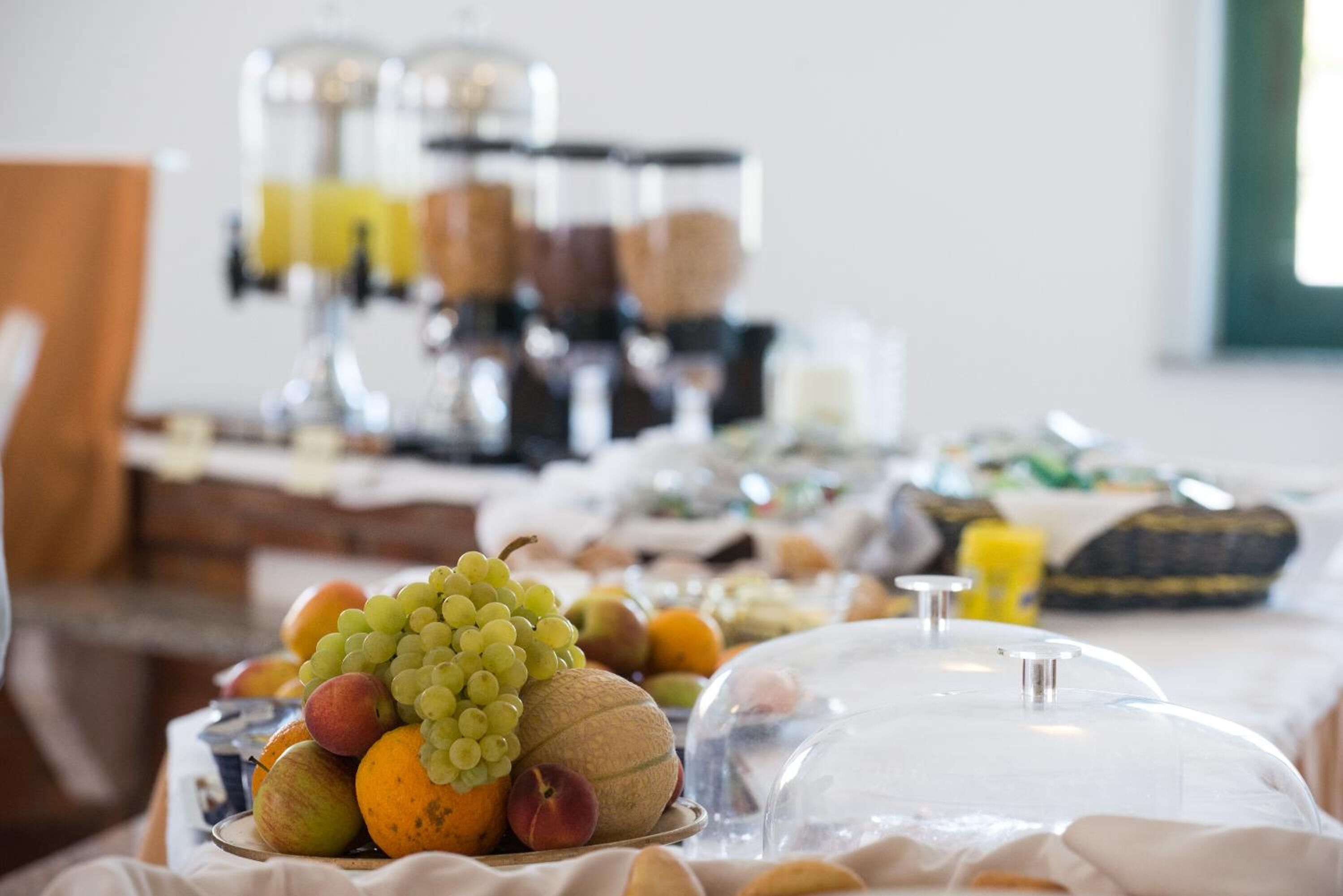 Un buffet proposant une variété de fruits et de plats présentés sous cloche, notamment des raisins, des pommes et des oranges.