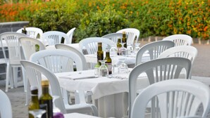 Outdoor dining tables with white plastic chairs, bottles, and glasses on a white tablecloth. - Villaggio Alkantara (Giardini Naxos)