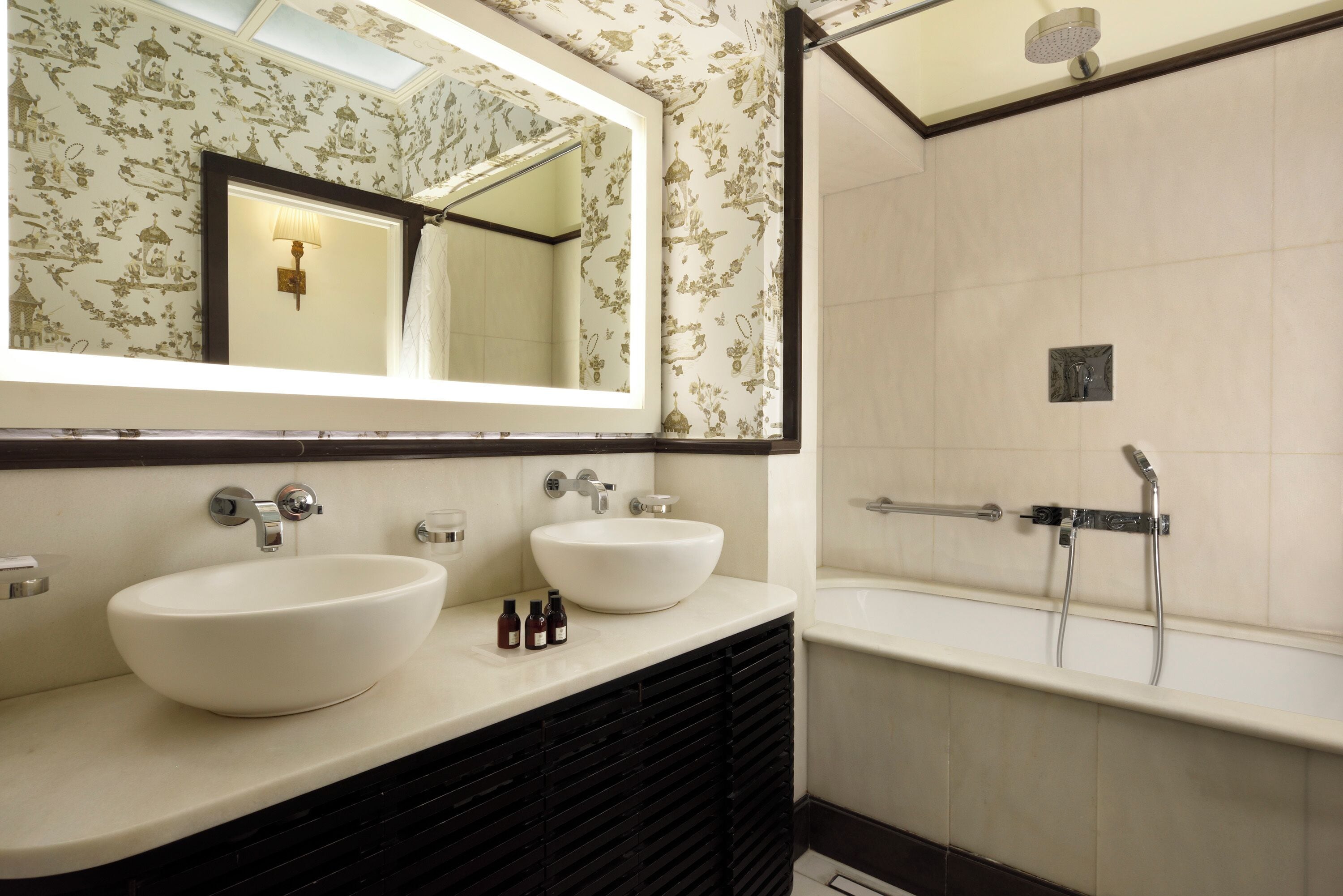 A bathroom with two sinks, a large mirror, and a shower.