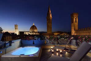 A rooftop terrace with a hot tub, lounge chairs, and flower planters. - San Firenze Suites & Spa (Florence)