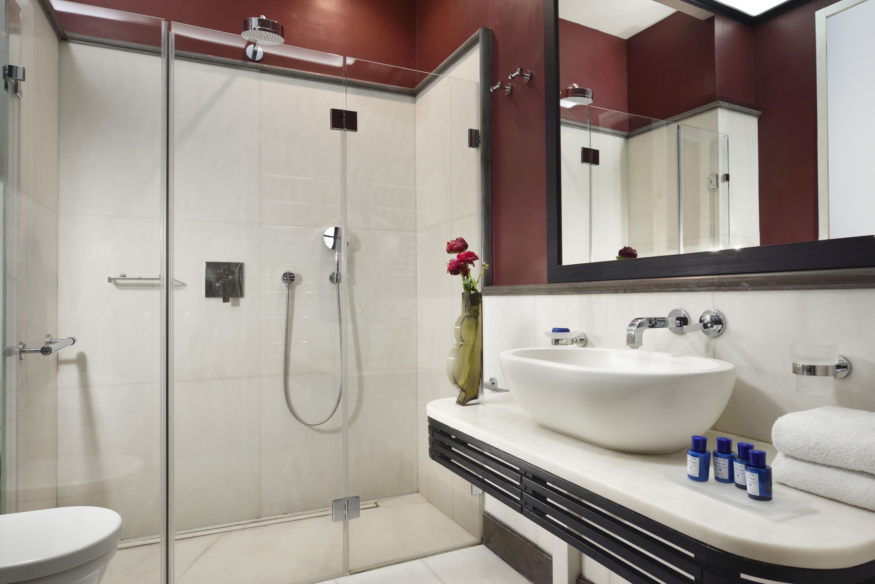A modern bathroom with a glass-enclosed shower, a white sink, and a large mirror.