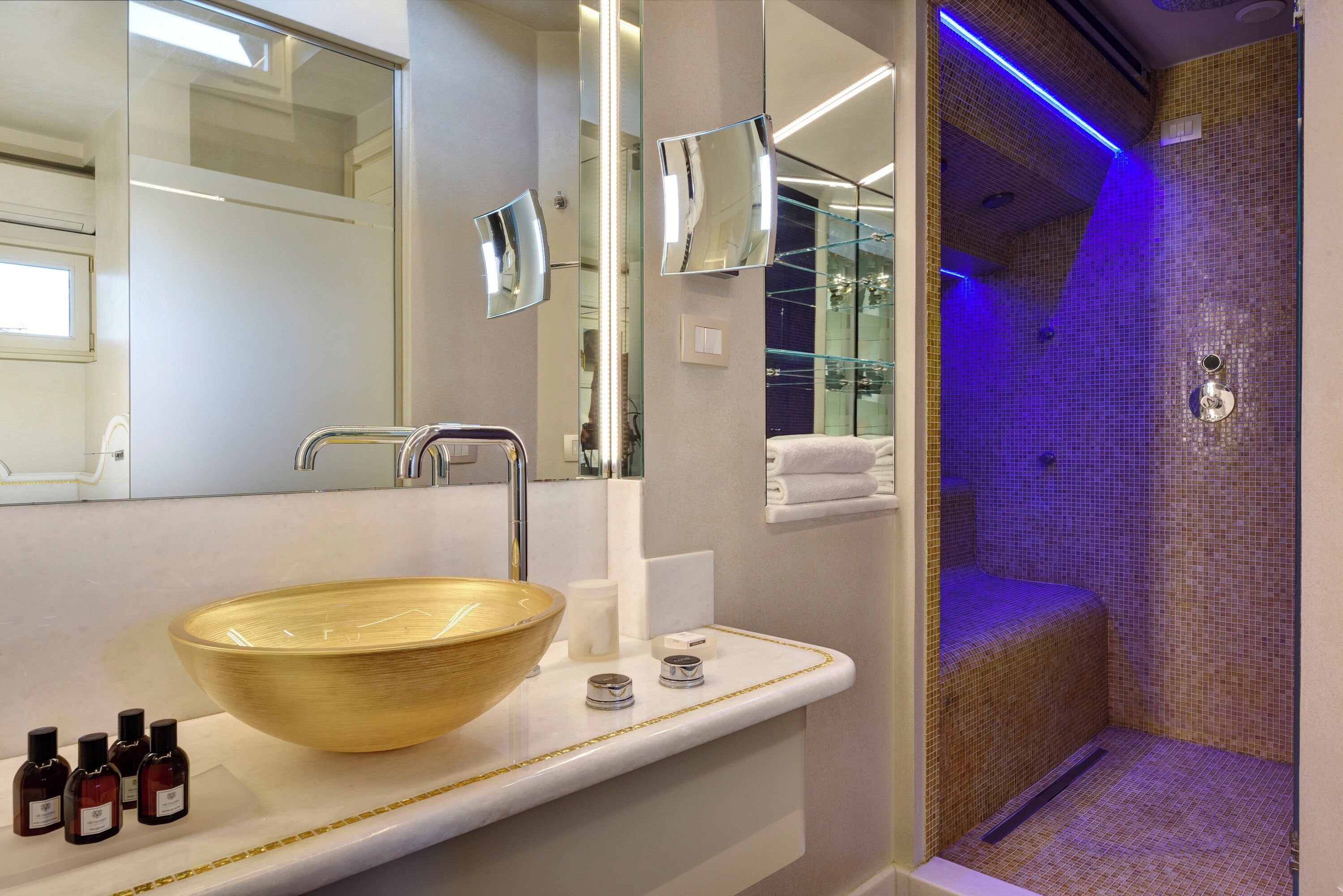 Un baño con un lavamanos de madera grande, un espejo y una ducha con mosaicos.